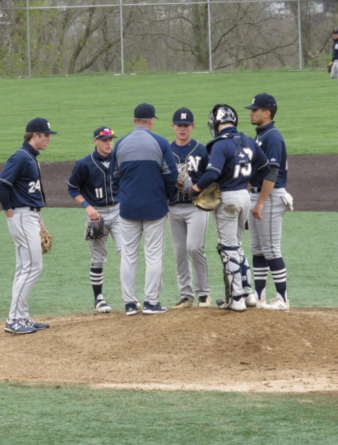 The team huddles together on the mound during a timeout. 