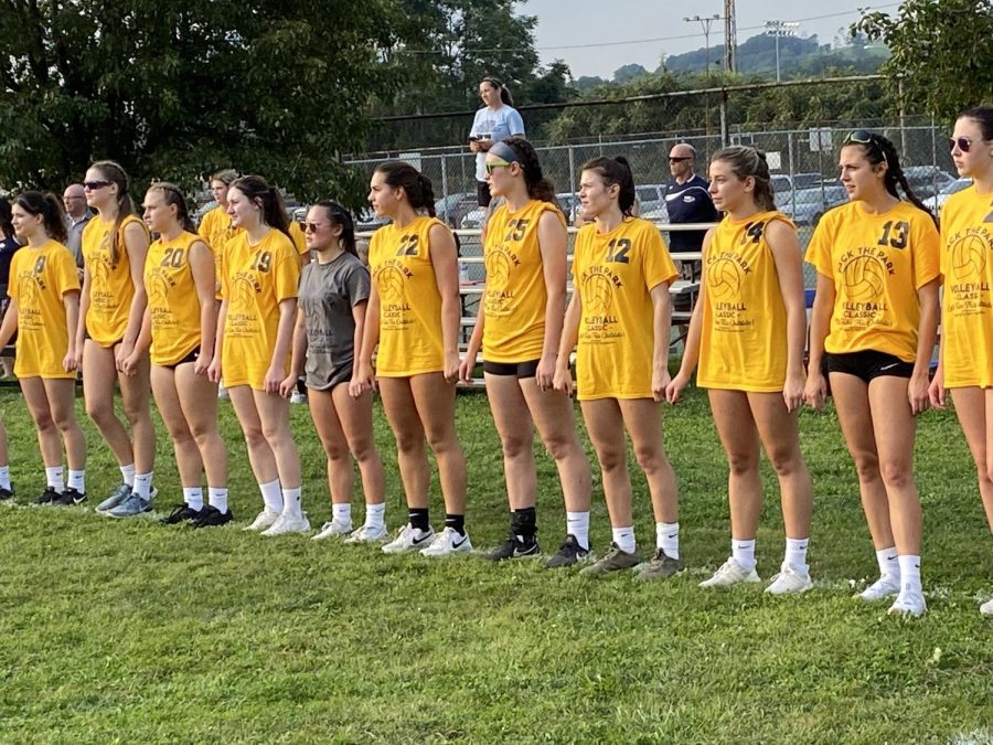 The Lady Knights volleyball team stands for the national anthem before their outdoor game against Kiski