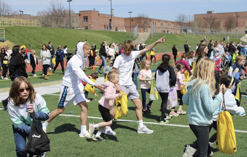 Children eagerly run onto the field to collect eggs.