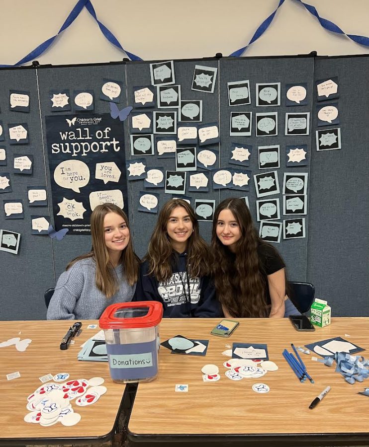 Sitting at the Children’s Grief awareness table, Juniors Kailey Resnik, Maria Janiga, and Madison Samber post encouraging messages on the bulletin. 