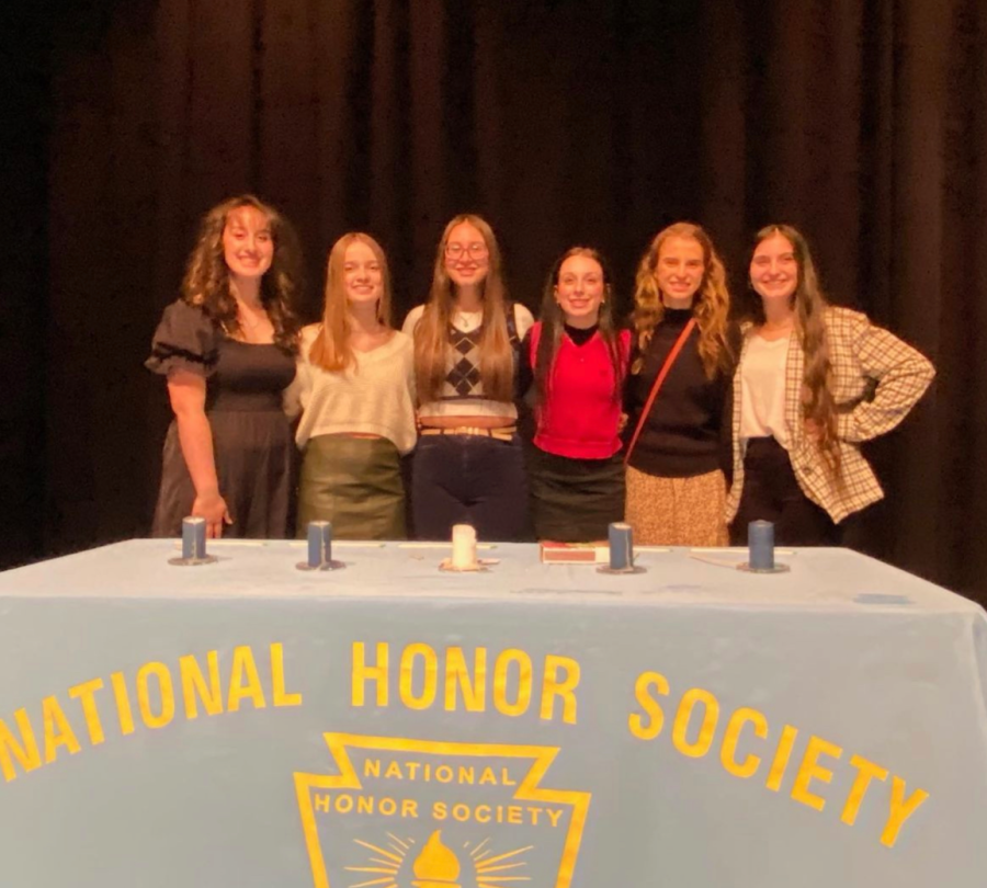 Nation Honor Society officers Abrielle Brown (12), Kailey Resnik (11), Olivia Todaro (11), Julianne Kellar (11), Abby Campbell (12), and Hannah Katona (12), stand onstage in front of the candles they light for the induction ceremony. 