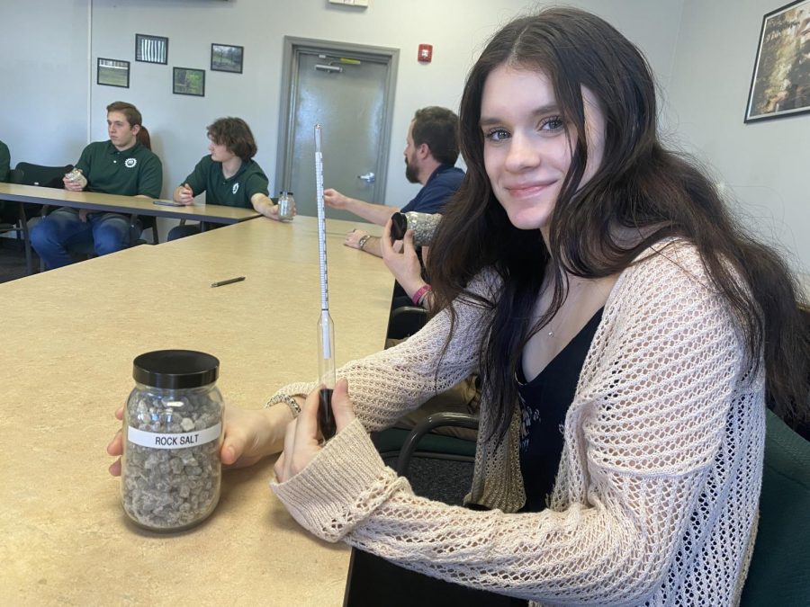 Genevieve Wills (12) poses for a picture with rock salt and a tool used in the creation of road salt. 