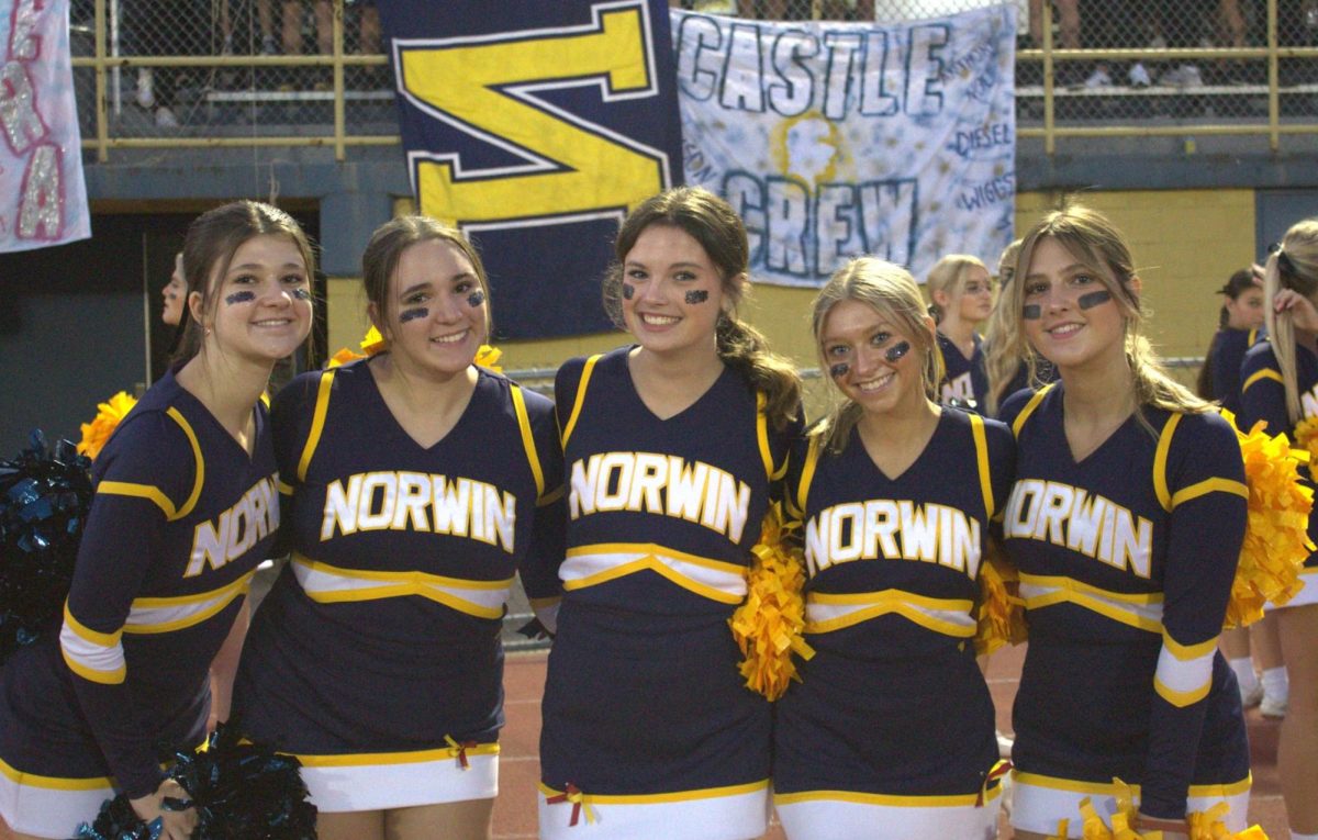 Members of the gameday cheer team in front of the castle crew at a home football game.