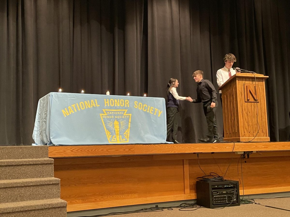NHS officer Julianne Kellar shakes hands with newly inducted sophomore Lucas Brahim at the NHS induction ceremony.