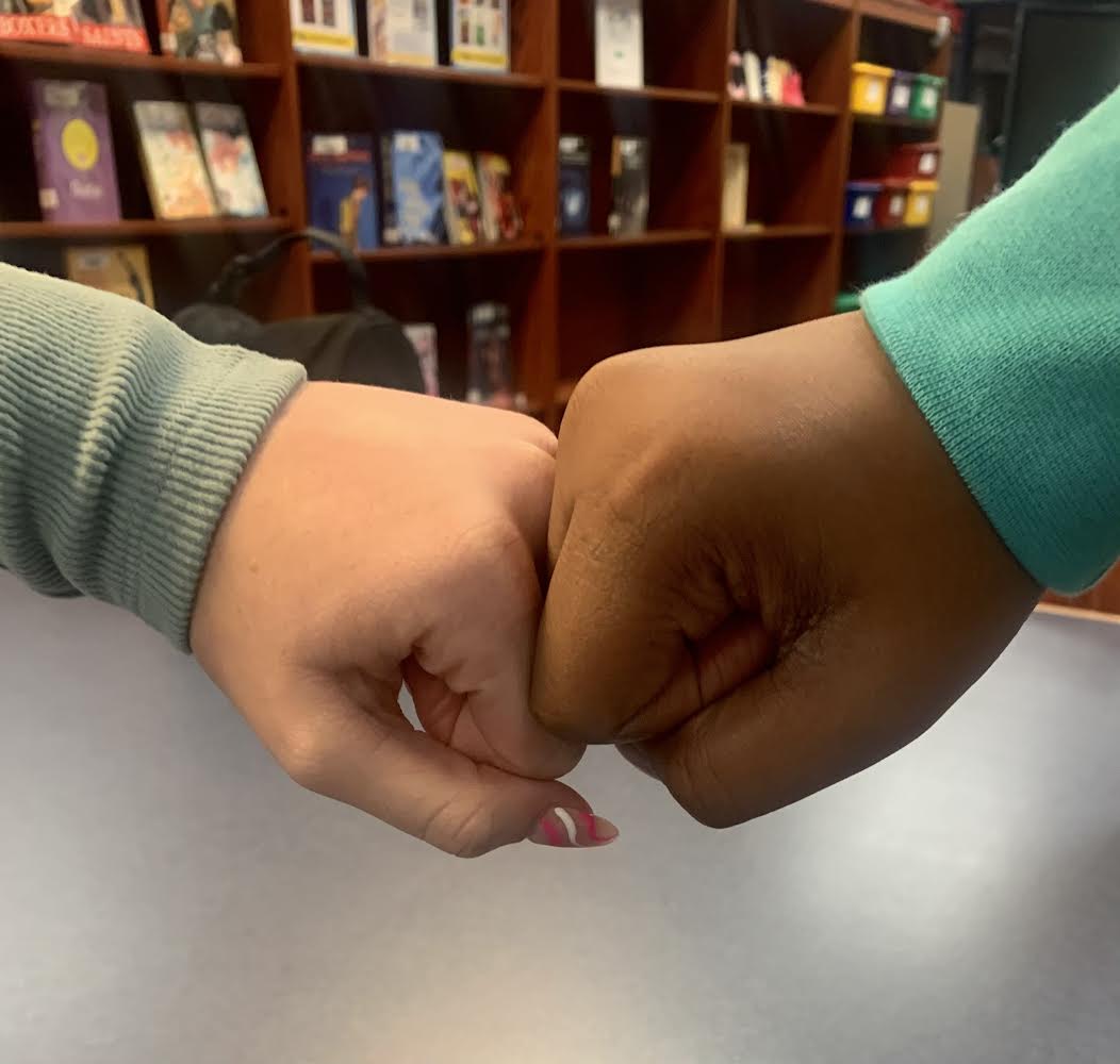 Students of different races fist bumping each other to show racial awareness.