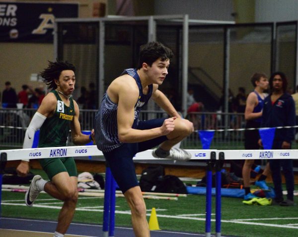 Freshman Tyler Beck bounds over the hurdle in his race.