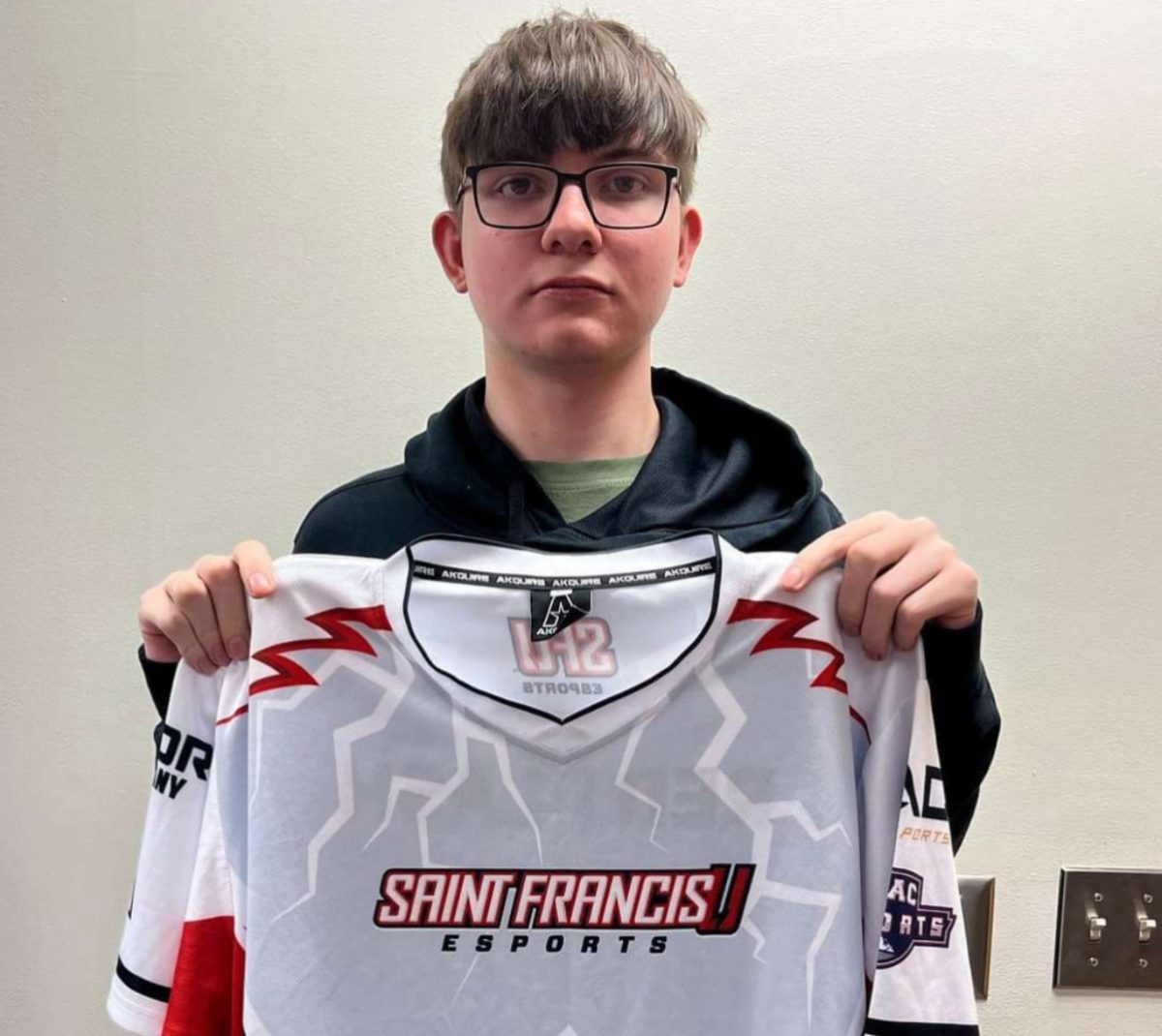Jacob+Hvozdik+poses+with+his+St.+Francis+Esports+game+jersey%2C+where+he+earned+a+4-year+scholarship+where+he+will+major+in+Coding.+