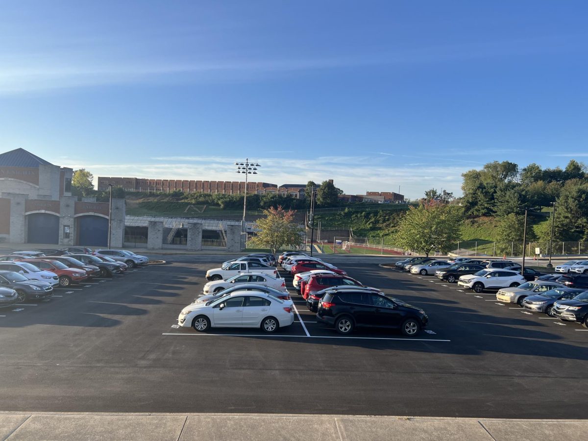 Faculty and student cars park in the freshly paved front parking lot.