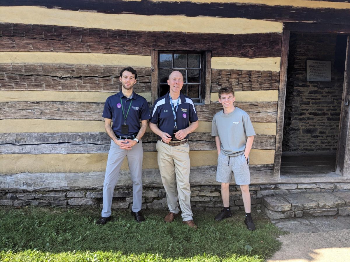 Student teacher Mr. Walker, Dr. Polen, and Landon Thomson (11) standing in front of a reconstructed storehouse.