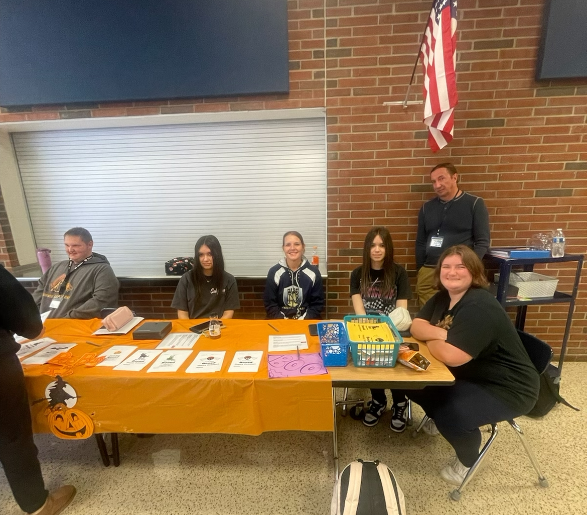 Mrs Haraburda, Chloe Cichowicz, Kaitlyn Cichowicz, Joey Hlavach, Summer Blessing, and Mr Hobbs work at the Peer Buddies booth during lunch.