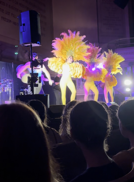 Performers dancing in their most vibrant and feathery attire of the show. 