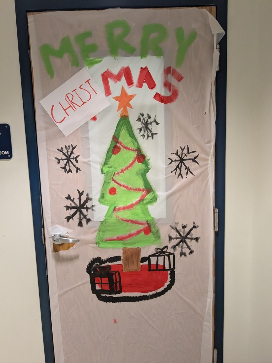 This door had a mostly green, white, and red color scheme. The door had a drawn holiday tree with some drawn black snowflakes. 