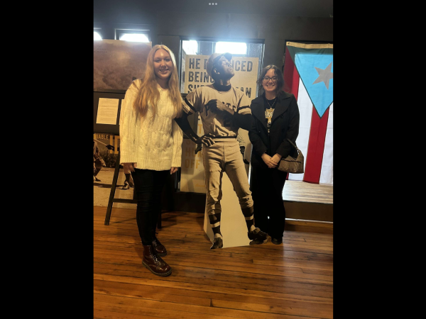 Gracie Paulovich and Grace Fleckenstein pose with a poster of Roberto Clemente in the museum. 